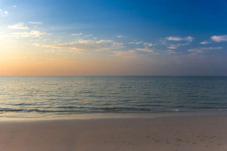 Empty white sandy beach and clear sea at early sunset.