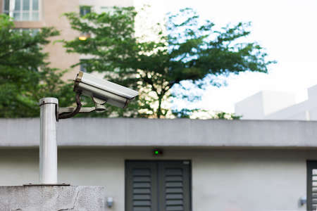 Grey CCTV camera mounted on top of a wall watching over an area.