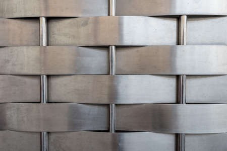 A close up of neat stainless steel band lengths woven around three stainless steel rods.の写真素材