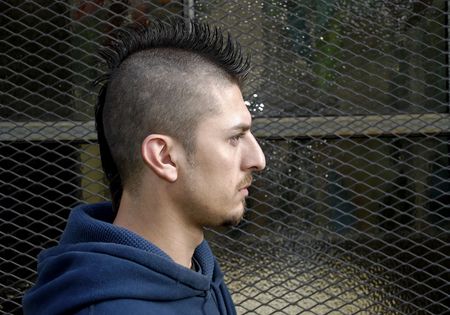Profile portrait of Hispanic  man with spiked Mohawk against a grudge background.の写真素材