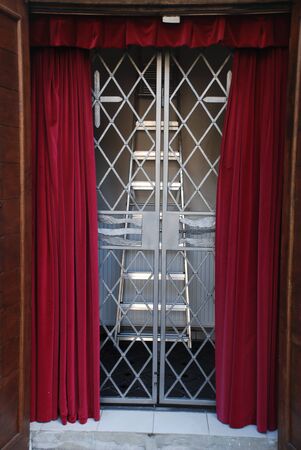 Red theater curtains with wavy  and the curtains pulled away. Also there are stairs and  grating.の写真素材