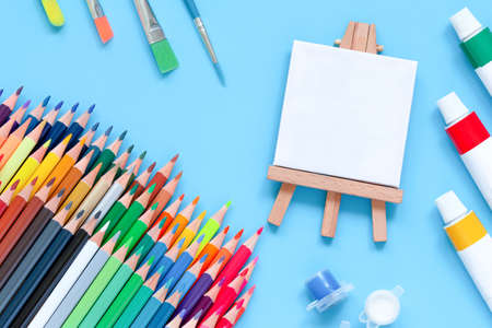 artist's set. easel with blanc canvas, colored pencils and paintsの写真素材