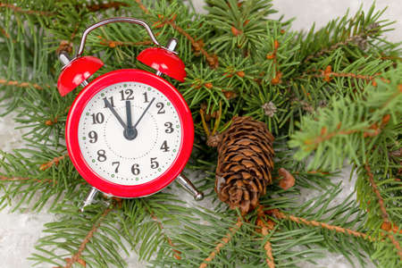 red clock on fir branches with a pine cone