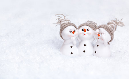 three white snowmen in gray hats, in the snowの写真素材