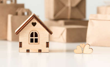 three wooden hearts and a house on the background of paper bags and boxesの写真素材