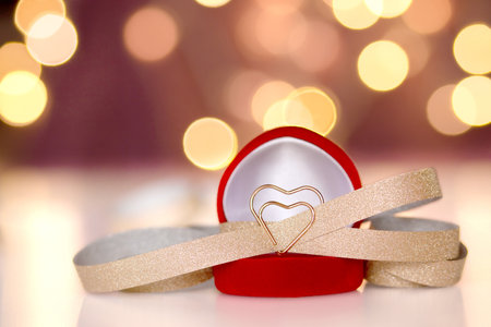 golden heart in a red gift box and gold ribbon on a background with bokeh