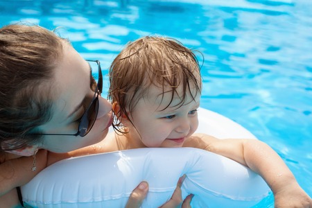 Young mother with her little daughter in the pool, learning to swimの写真素材