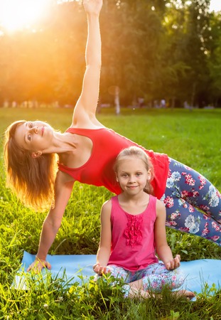 Mother and her daughter outdoors doing yoga, healthy lifestyleの写真素材