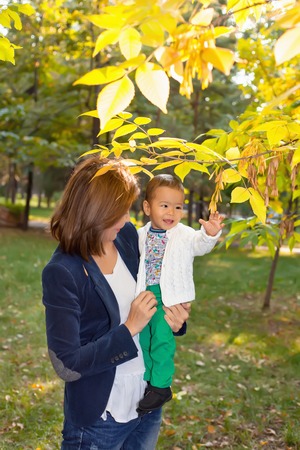 Asian Granny playing with her grandson in the Park, holding him in my hands near the treeの写真素材