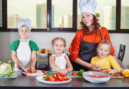 Three cute kids with mom making fruit salad in the kitchen. Healthy eatingの写真素材
