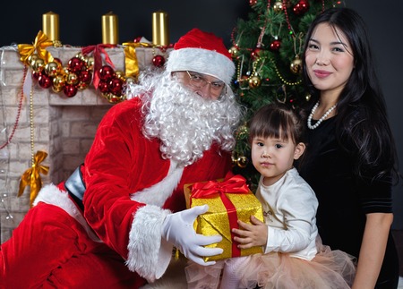 Santa Claus and mother with your child dress. Christmas Scenes. The Child holding gift box Packedの写真素材