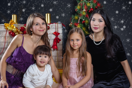 Lesbian interracial family in the background of Christmas. Two moms with their daughters.の写真素材