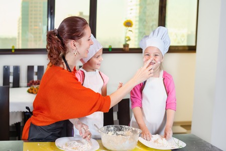Lovely children together with mother preparing a cake of dough in the kitchen. Healthy eatingの写真素材