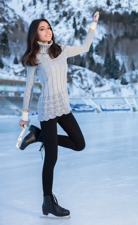 Pretty woman ice skating winter outdoors, smiling facial. Close-up outdoors, mountains in the backgroundの写真素材