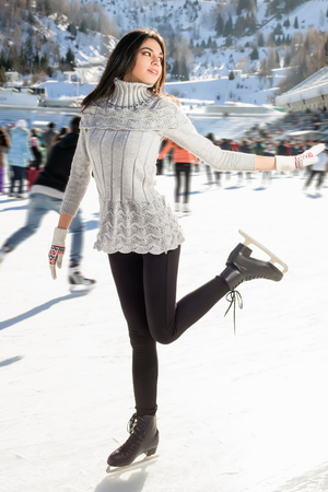 Pretty woman ice skating winter outdoors, smiling facial. Close-up outdoors, mountains in the backgroundの写真素材