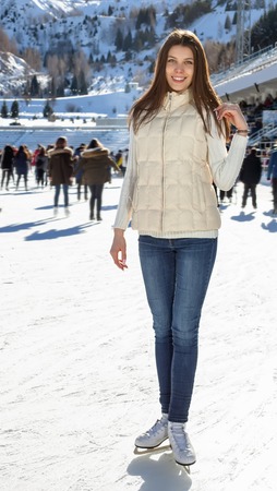 Pretty woman ice skating winter outdoors, smiling facial. Close-up outdoors, mountains in the backgroundの写真素材
