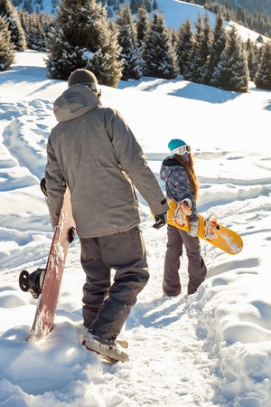 Couple snowboarder Down the mountain. Mountains in the backgroundの写真素材