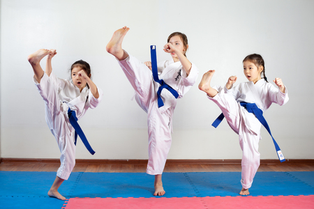 Three little girls demonstrate martial arts working together. Fighting position, active lifestyle, practicing fighting techniquesの写真素材