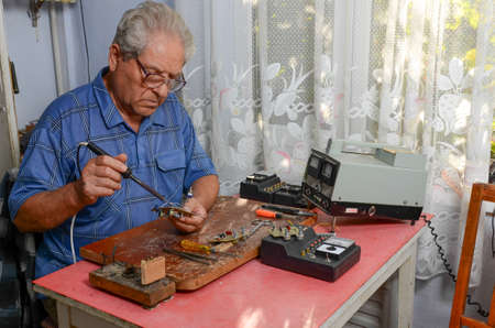 grandfather working with a soldering ironの写真素材