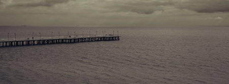 A panorama of a pier in the sea under a cloudy sky