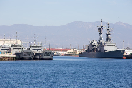 Naval ships are tied up at the dock  Two ships to the right appear to be sea to land infantry or vehicle trasporation  The ship on the right appears to be a battleship or cruiser のeditorial素材