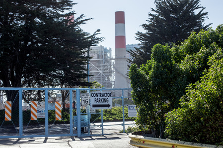 A large smoke stack dominates the entrance of a Southern California power plant 