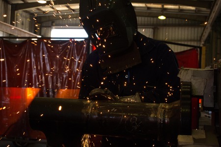 A skilled welder is grinding on a pipe joint の写真素材