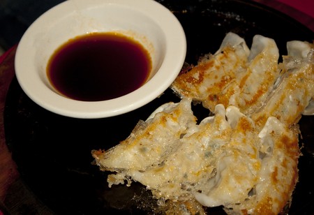 Plate of gyoza potstickers on a white plate with sauce on sideの写真素材