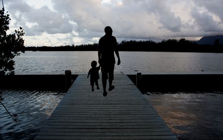 father and son walking on a pier at duskの写真素材