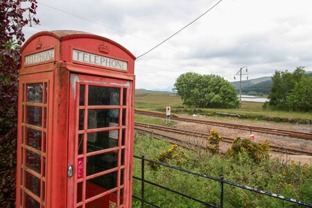 Red phone booth near rail tracks in the UK