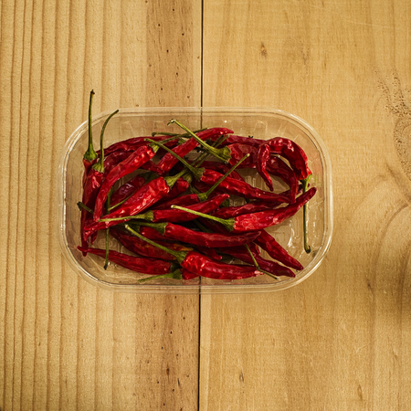 Red hot chili pepper in a transparent box on wooden background.の写真素材