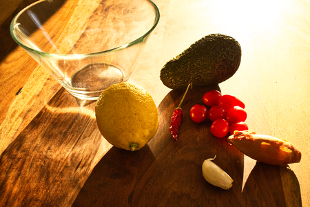 Ingredients for a guacamole. Chili, lemon, onion and avocado on a wooden table. Homemade Mexican...