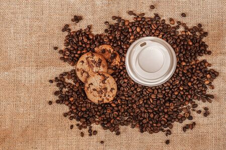 coffee for going with chocolate cookies and coffee beans on a jute bag, top viewの写真素材