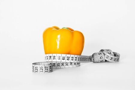 concept of diet - yellow pepper with measuring tape isolated on white backgroundの写真素材