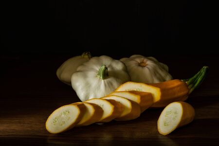 Chiaroscuro. Sliced ââzucchini and three pastinas on a wooden table with black background.の写真素材