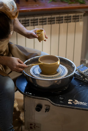 Hands of a potter making a cup of coffee on a pottery wheelの写真素材