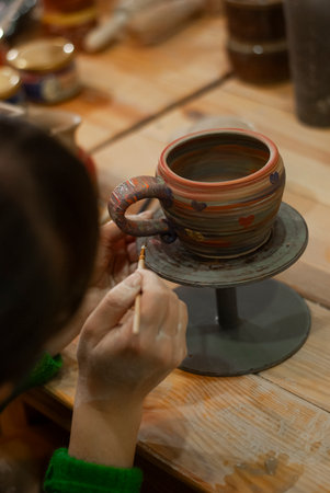 Potter creating a cup of clay on a pottery wheel.