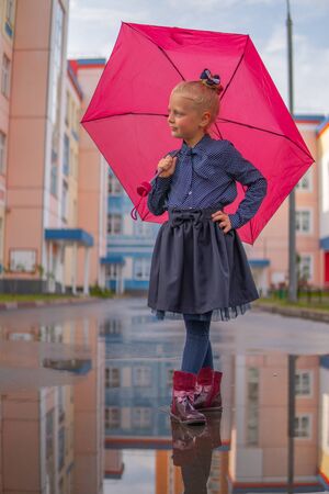 Girl in her hands holds a red umbrella and a puddle, parkの写真素材