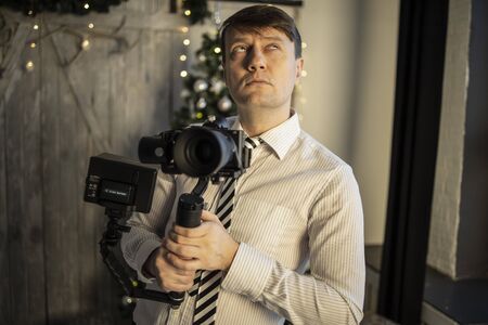 A beautiful young photographer on a colored background holds a camera and a candy bar, takes off...