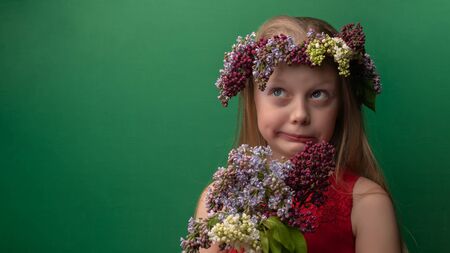 Auspicious youthful wonderful in a lilac wreath with white skin rejoices background green. Grimaceの写真素材