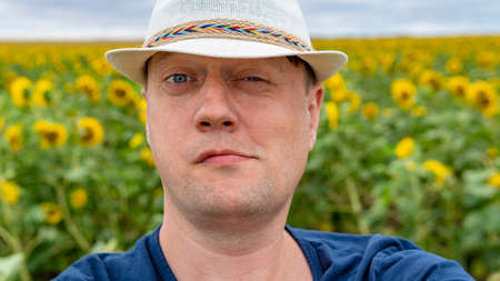 The guy in the cap on the field with sunflowers in the summer