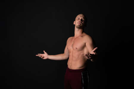 The guy dissatisfied spreads his hands pumped against a black background