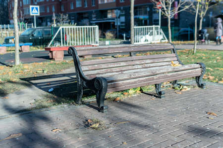 A bench in the shade of a wooden in the park in the background of the car on stone stylingの写真素材