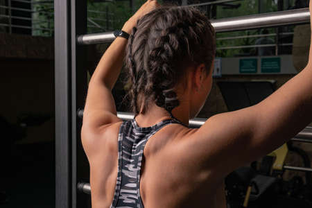 The girl leans against the sports stairs in the dark. Metallic in a beautiful shape of a gym of a...