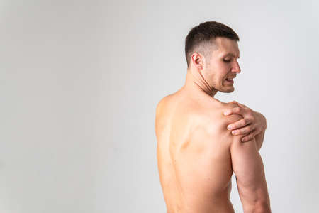 A sore shoulder joint muscle in a white man on a white background pain   ill person  massage   chronic.  Hold   ain  suffer attractiveの写真素材
