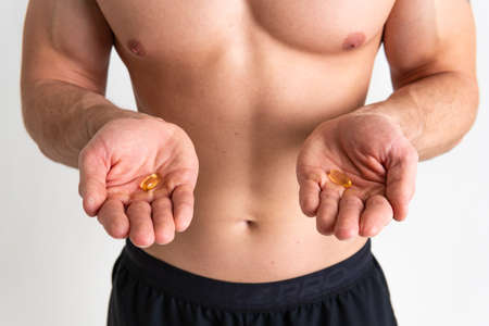 Fish oil is eaten by a man in the hands of vials and a glass bottle health supplement, omega diet pharmaceutical cure omega, young closeup. smile translucent, health female giving dietingの写真素材