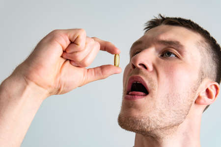 Fish oil is eaten by a man in the hands of vials and a glass bottle fish health supplement, treatment medical yellow medication People isolated care female giving dietingの写真素材