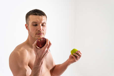 Man holds apples in fitness white background isolated  isolated body,  sexy young muscle background,  nude.  Guy hold  wellness  chestの写真素材