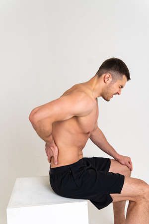 A man sits back pain keeps his hand on his back painful, cramp spine isolated stress, human Tension care, back suffer attractiveの写真素材