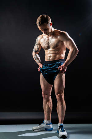 Man on black background keeps dumbbells pumped up in fitness active body strong lifting person Attractive skin metal, people fit muscles on the torso of the abs and legs biceps in roll growthの写真素材